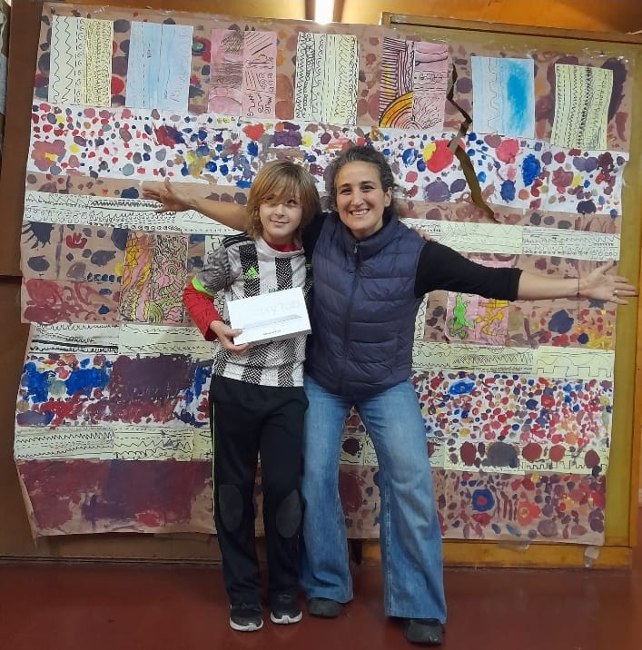 Niño feliz junto a su nueva tablet y su mamá en la escuela.